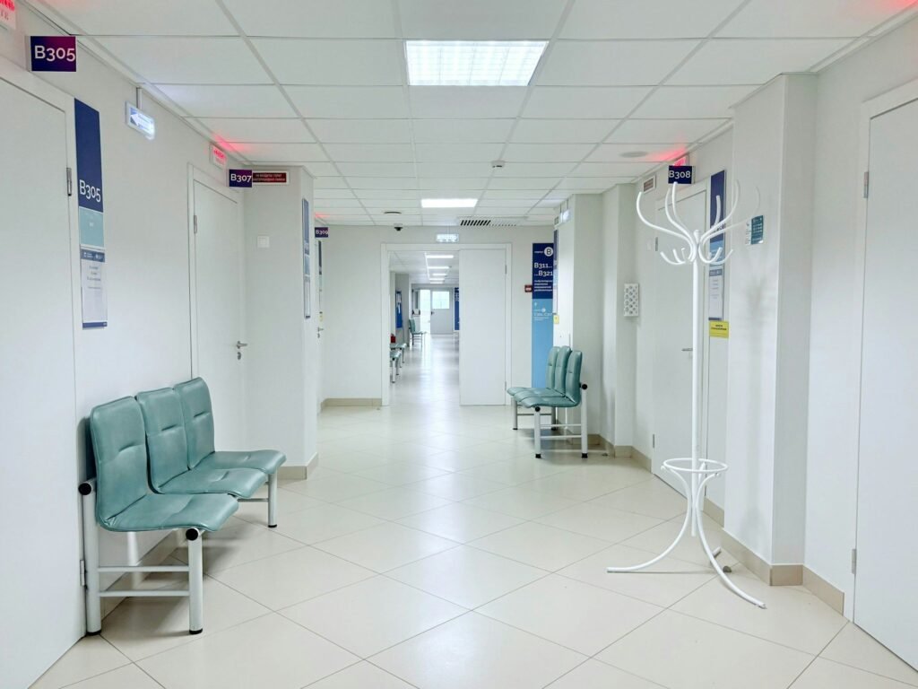 Clinical corridor with seating, numbered room signs and clear circulation