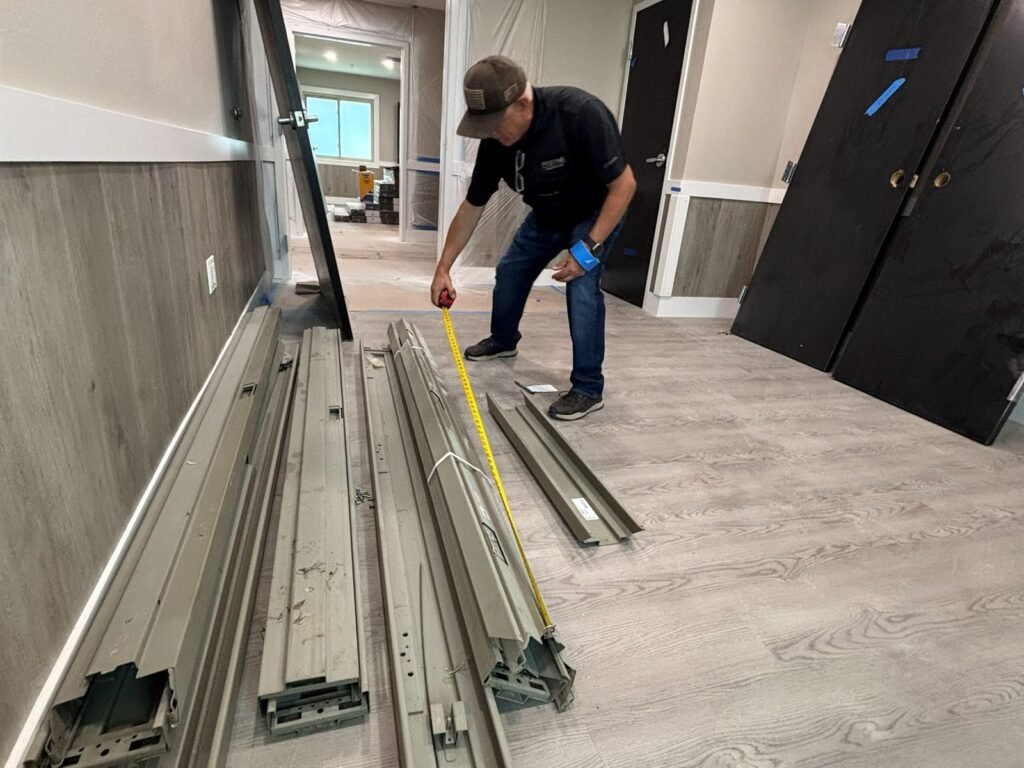 Pristine team member measuring metal framing sections inside a corridor