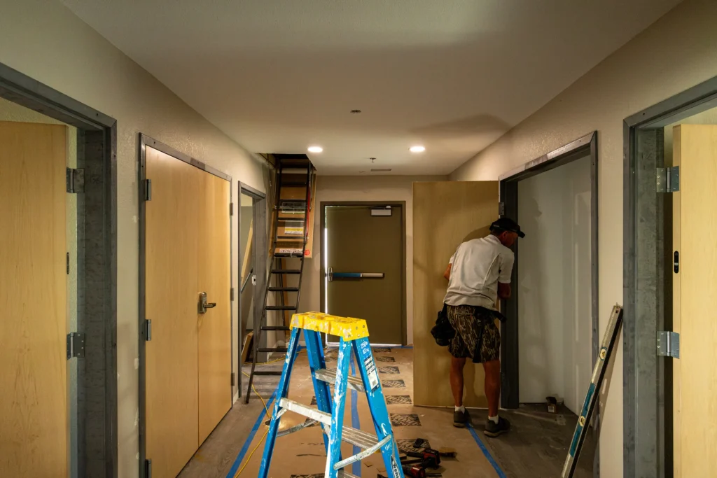 Crew member working at a doorway in a corridor under renovation