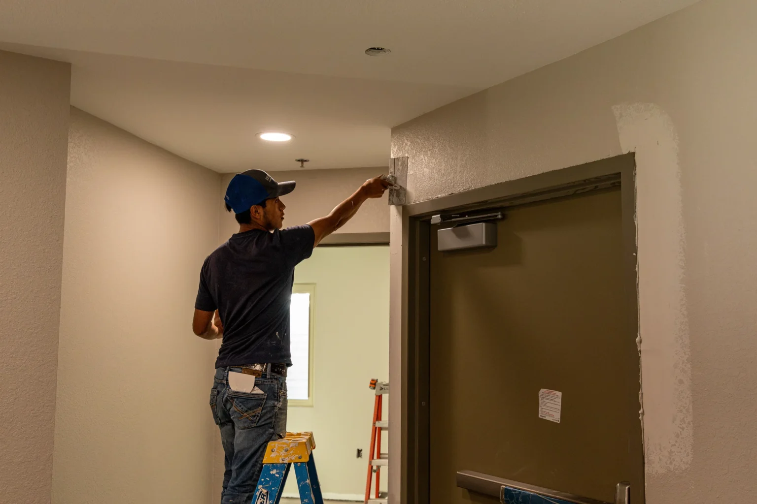Crew member finishing the wall surface around a doorway