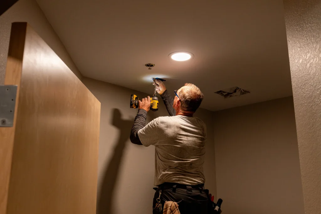 Crew member working on ceiling fittings during renovation