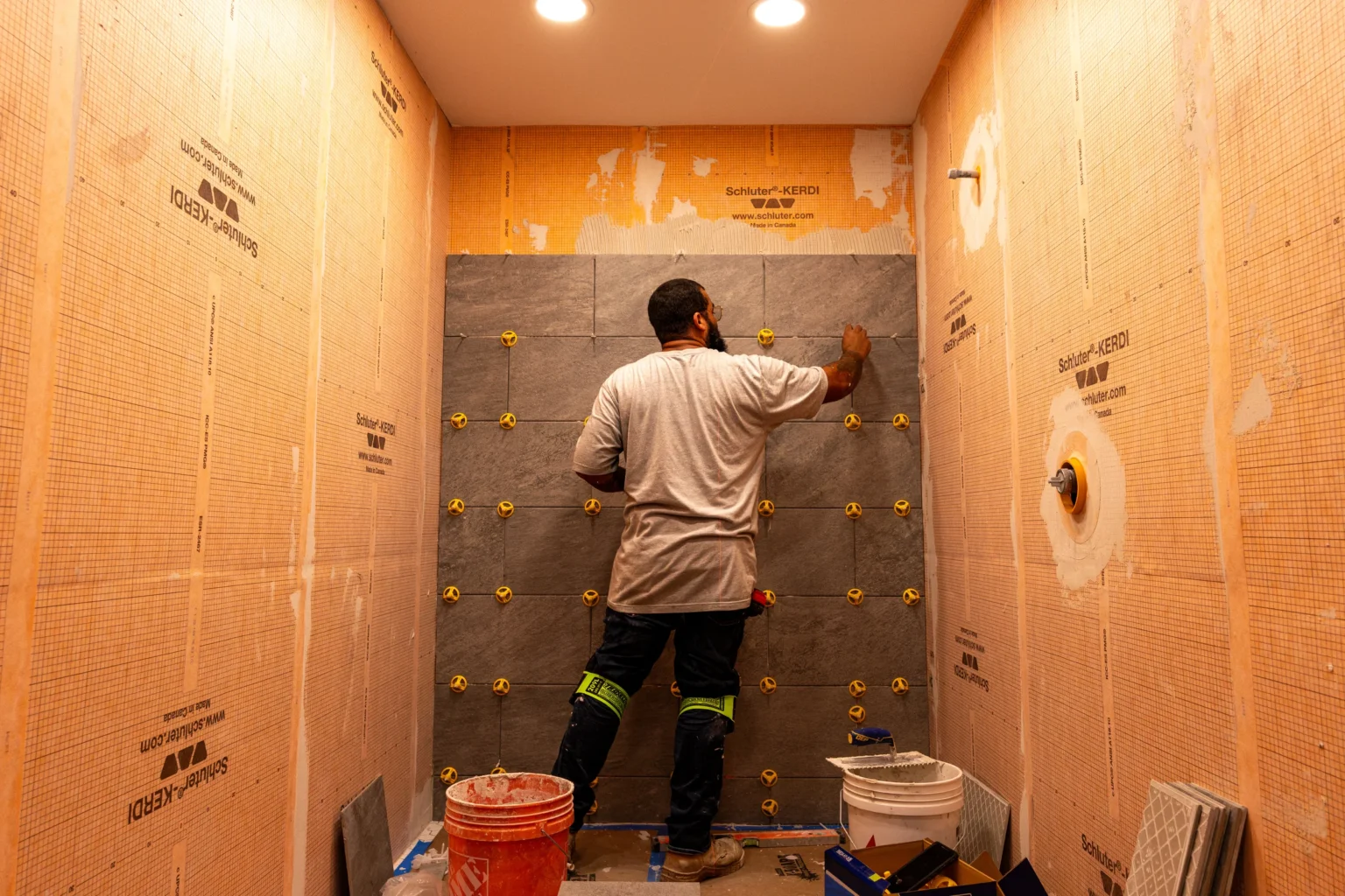 Tile installer aligning wall tiles with spacers in a prepared work area