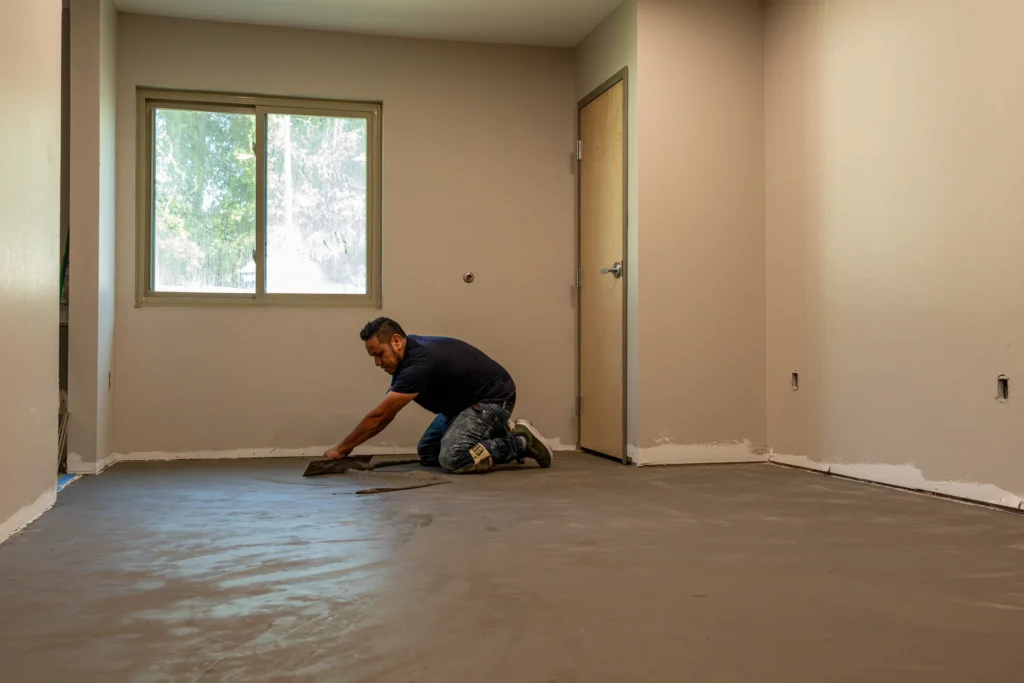 Crew member preparing the floor within a single room under renovation