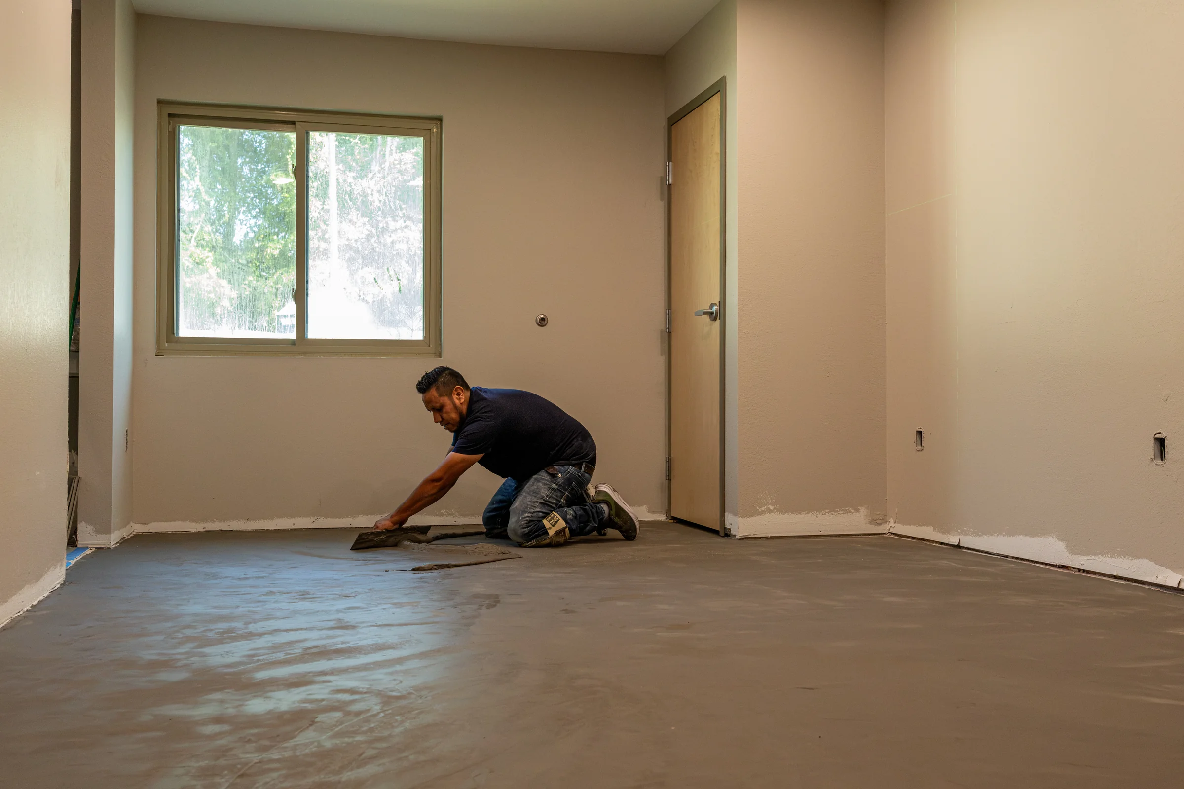 Crew member preparing the floor within a single room under renovation